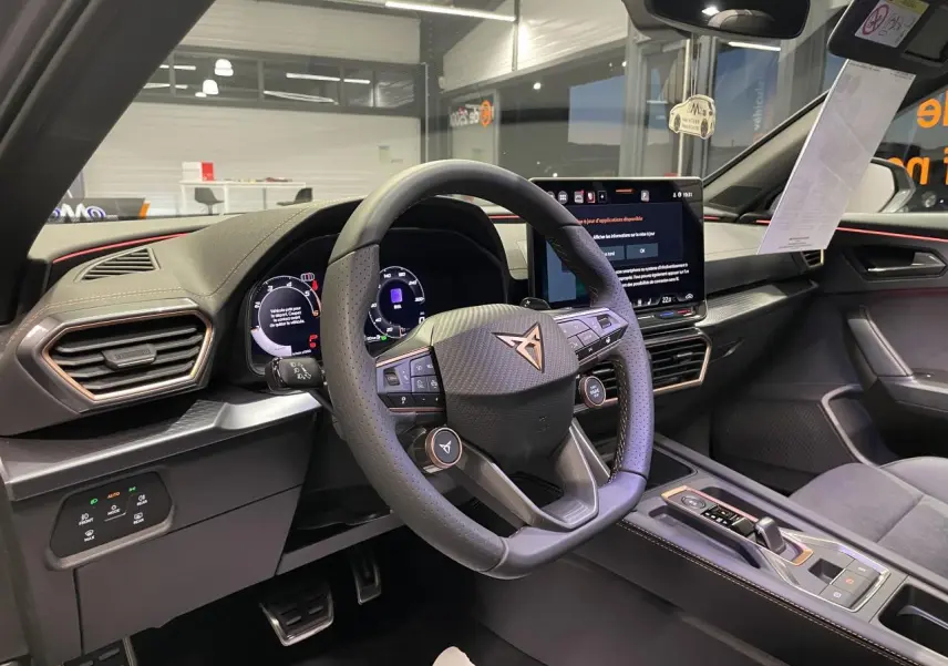 Vue intérieure du poste de conduite du CUPRA Formentor 2026, volant cuir perforé avec logo cuivré et écran tactile central.