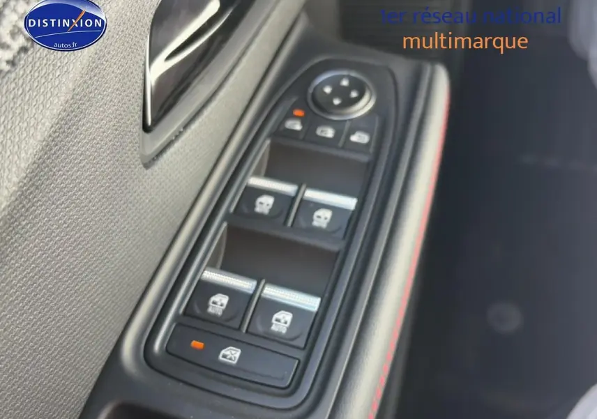 Gros plan sur les commandes des vitres côté gauche de la Renault Clio VI noire, avec surpiqûres rouges visibles.