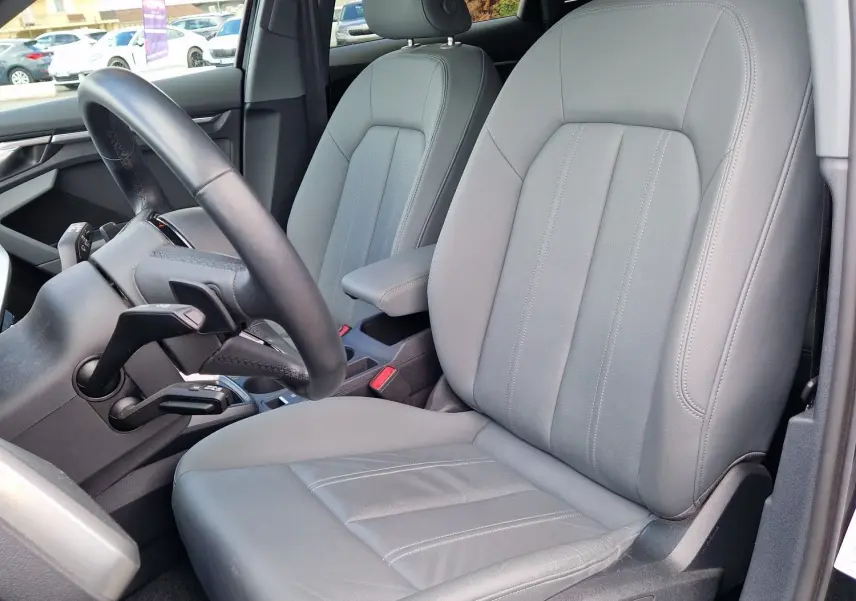 Vue intérieure côté conducteur de l'Audi A3 Sportback noire 2021, mettant en valeur les sièges en cuir gris et le volant.