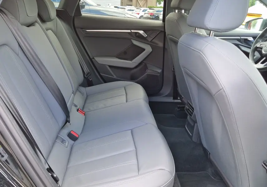 Vue intérieure côté gauche montrant les sièges arrière en cuir gris clair de l'Audi A3 Sportback noire.