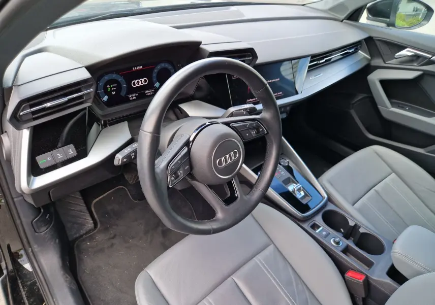 Vue intérieure côté conducteur de l'Audi A3 Sportback 40 TFSI-e 2021, tableau de bord numérique et sellerie cuir gris clair.