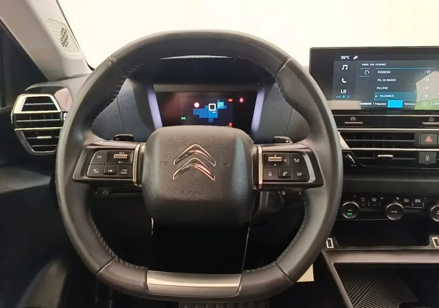 Vue intérieure centrée sur le volant cuir multifonctions noir du Citroën C4 X avec tableau de bord digital et écran tactile.