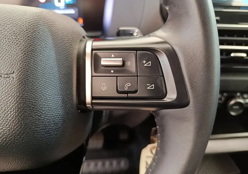 Gros plan sur le côté droit du volant cuir noir de la Citroën C4 X 2023 avec commandes multifonctions.