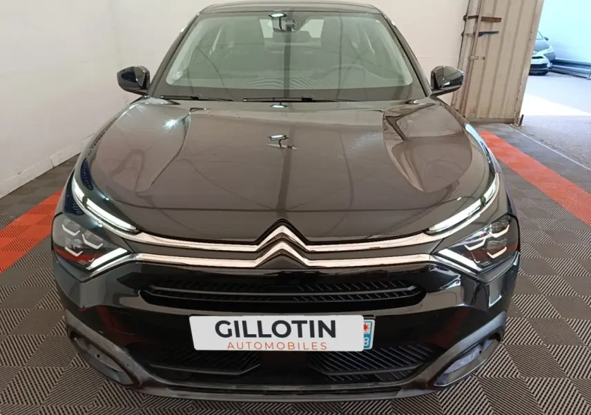 Vue avant d'une Citroën C4 X noire 2023 avec calandre chromée et phares LED distinctifs dans un garage.