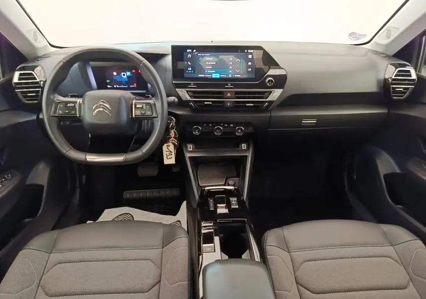 Vue intérieure avant du tableau de bord noir de la Citroën C4 X avec volant cuir multifonctions et écran tactile central.