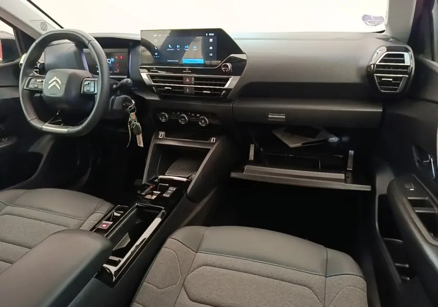Intérieur noir de la Citroën C4 X 2023, vue du poste de conduite avec volant cuir multifonctions et écran tactile central.