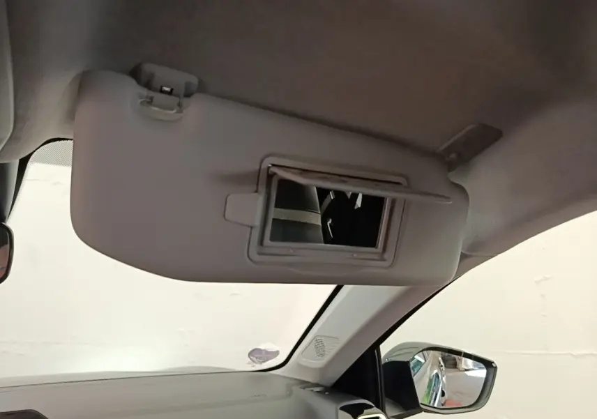 Détail intérieur montrant le pare-soleil côté conducteur avec miroir intégré et rétroviseur extérieur noir.