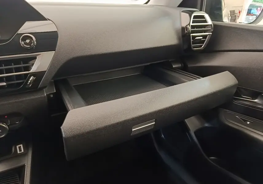 Intérieur de la Citroën C4 X noir, vue du tableau de bord côté passager avec boîte à gants ouverte.