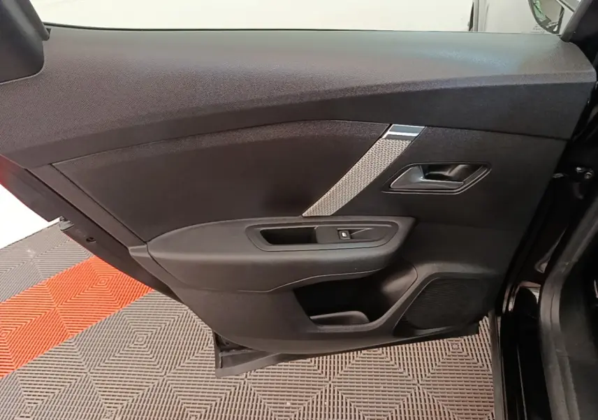 Vue intérieure de la porte avant gauche noire du Citroën C4 X 2023 avec poignée et commande de vitre intégrées.