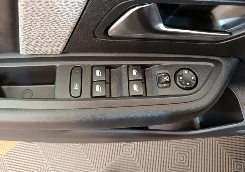 Gros plan sur la commande des vitres et rétroviseurs côté conducteur du Citroën C4 X noir, intérieur tissu et plastique noir.