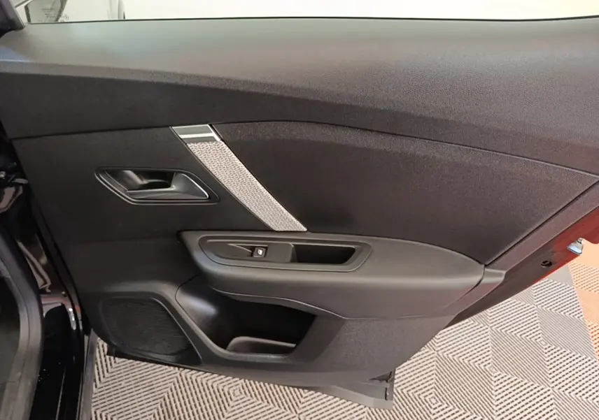 Vue intérieure de la porte arrière gauche noire d'une Citroën C4 X 2023, avec poignée et commande de vitre.