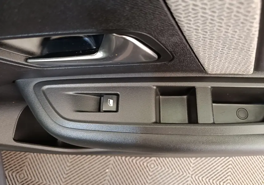 Gros plan sur la poignée intérieure et commande de lève-vitre côté conducteur d'une Citroën C4 X noire.