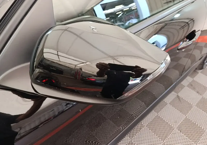 Rétroviseur droit noir brillant de la Citroën C4 X 2023, avec poignée de porte et carrosserie noire en reflet.