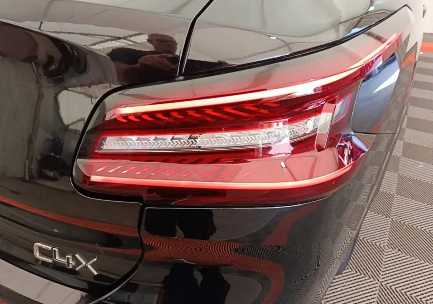 Gros plan sur le feu arrière droit rouge d’une Citroën C4 X noire, avec logo C4 X visible sur le coffre.
