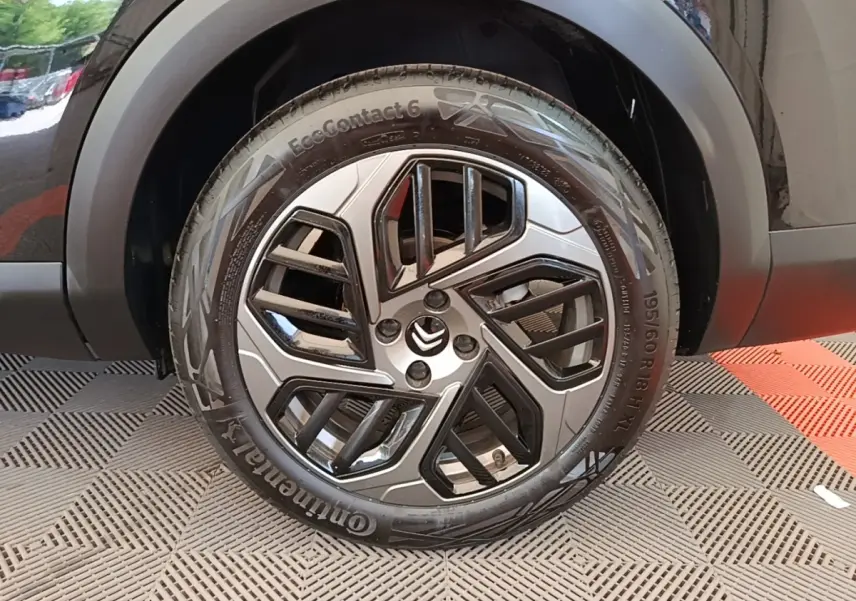 Gros plan sur la roue avant droite noire d'une Citroën C4 X 2023 avec jante alliage au design moderne.