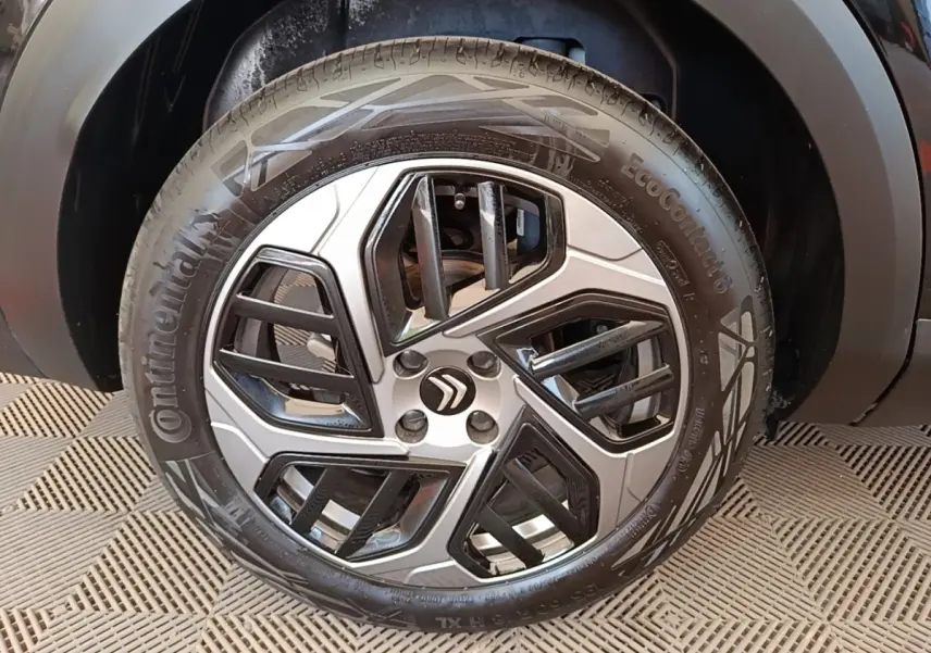 Gros plan sur la roue avant droite d’une Citroën C4 X noire, mettant en valeur la jante alliage au design géométrique.