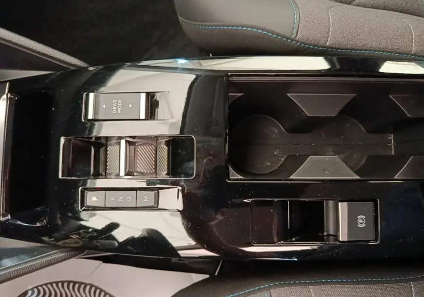 Vue rapprochée de la console centrale noire brillante de la Citroën C4 X avec commandes de boîte auto et porte-gobelets.