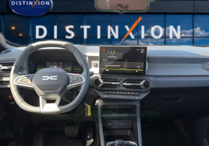 Vue intérieure avant du tableau de bord du Dacia Duster 2026 avec volant multifonction et écran tactile central.