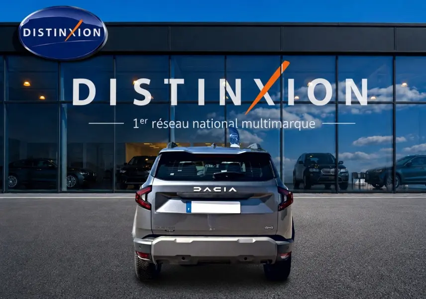 Vue arrière d'un Dacia Duster gris schiste 2026 avec logo DACIA et badge 4x4, devant une vitrine Distinxion.