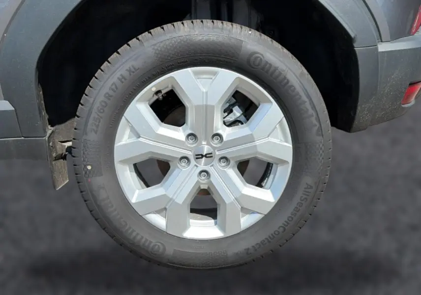 Gros plan sur la roue arrière droite du Dacia Duster gris schiste, avec jante alu à design hexagonal.
