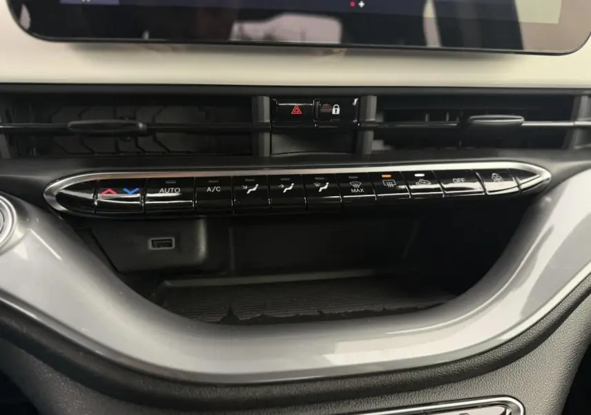 Vue rapprochée de la console centrale de la Fiat 500 électrique blanche, mettant en valeur les commandes de climatisation et l'écran tactile.