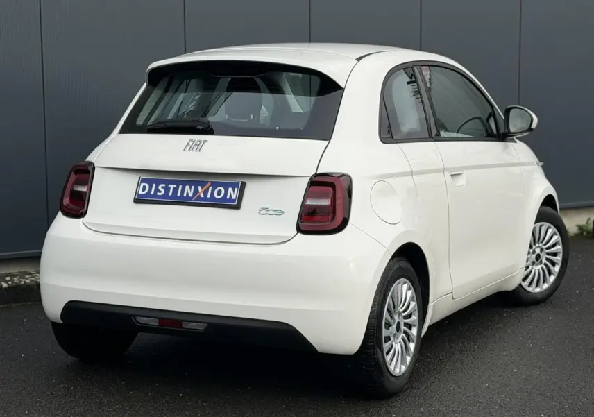 Vue 3/4 arrière droite d'une Fiat 500 électrique blanche 2024 avec feux arrière foncés et jantes multibranches.