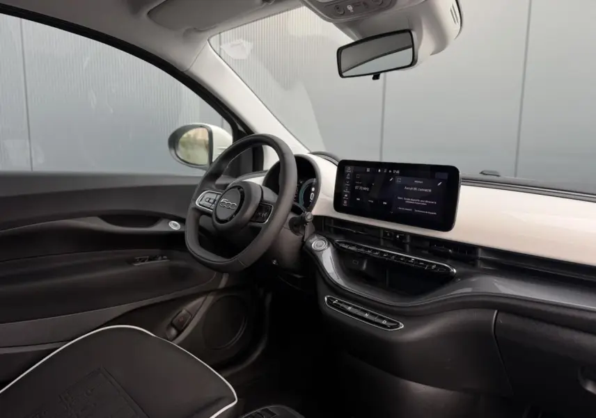 Intérieur avant droit de la Fiat 500 électrique blanche 2024, avec tableau de bord moderne et écran tactile horizontal.