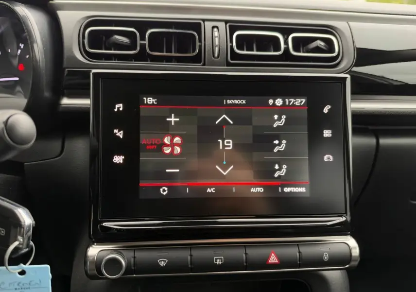 Vue rapprochée de l’écran tactile central et des commandes de climatisation d’une Citroën C3 blanche Banquise 2024.