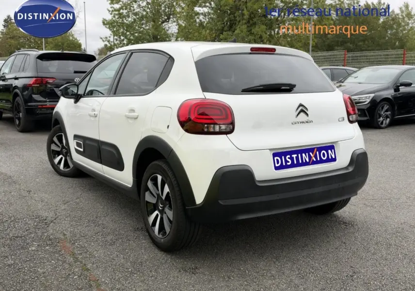 Citroën C3 blanc Banquise vue 3/4 arrière droit avec jantes alu et protections noires sur parking.