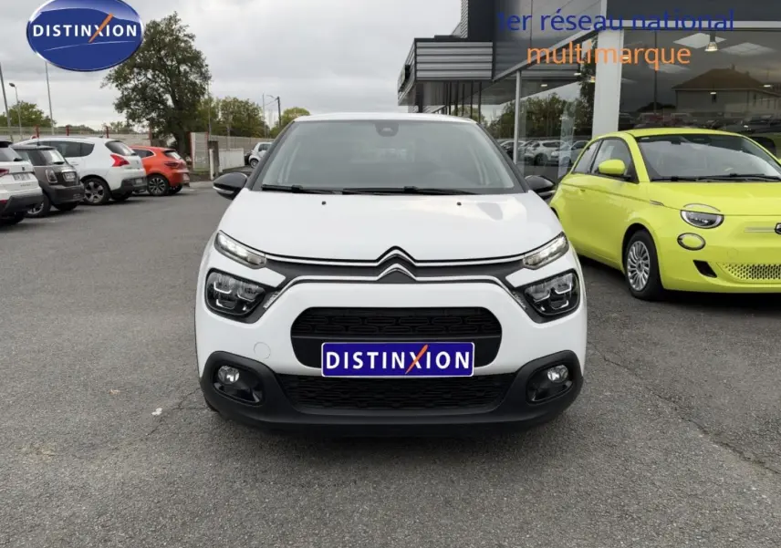 Vue avant d'une Citroën C3 blanche Banquise avec calandre noire et phares LED, stationnée devant un showroom.