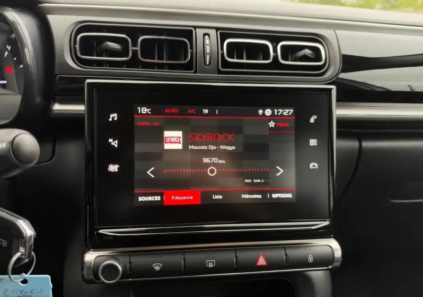 Vue rapprochée de l’écran tactile central de la Citroën C3 2024 affichant la radio Skyrock, entouré de commandes et aérateurs noirs.