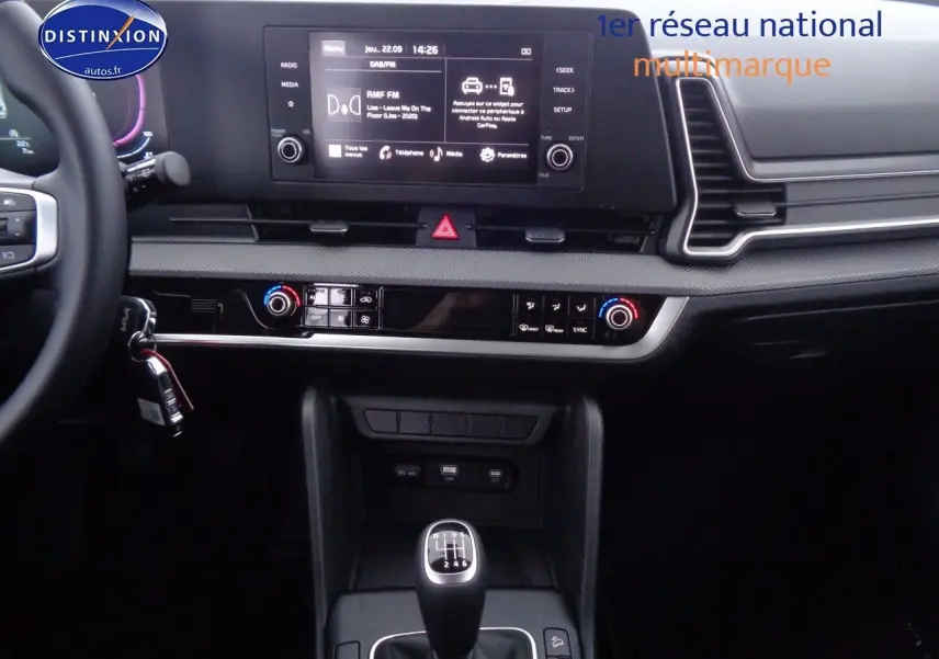 Vue intérieure centrée sur la console centrale du Kia Sportage 2022, avec boîte manuelle et écran tactile multifonction.