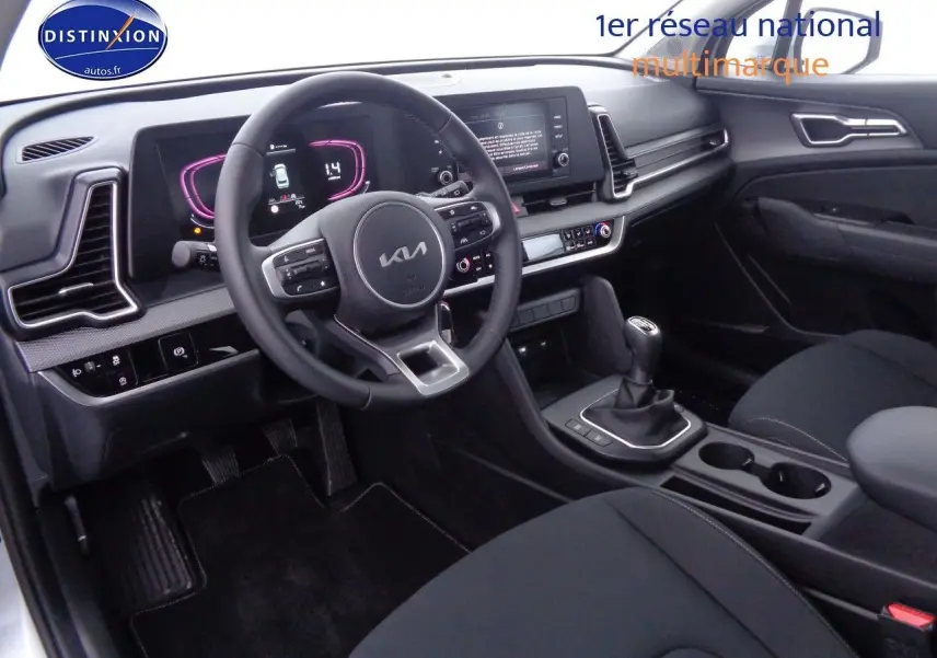 Vue intérieure côté conducteur du Kia Sportage 2022, volant multifonction et boîte manuelle dans un habitacle noir moderne.