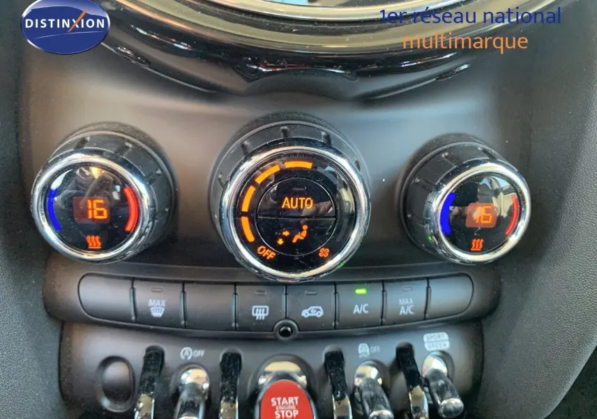 Gros plan sur les commandes de climatisation automatique du MINI rouge chili, avec affichage numérique et boutons chromés.