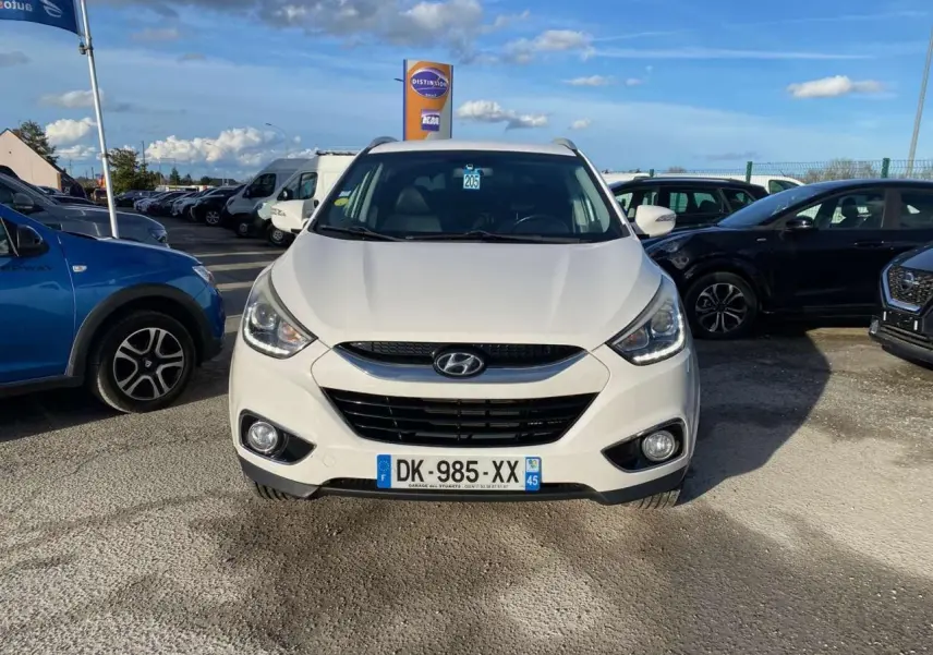 Vue de face d'un Hyundai ix35 blanc stationné, avec ses projecteurs et calandre distinctifs visibles.