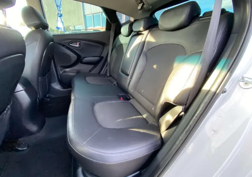 Vue intérieure côté arrière droit montrant la banquette en cuir noir du Hyundai ix35 blanc de 2014.