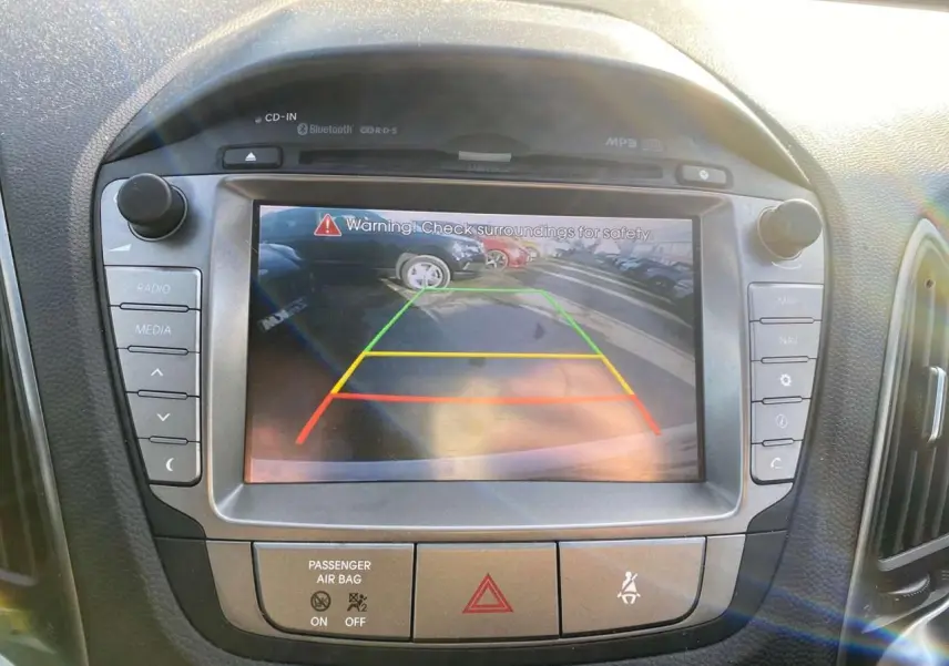 Écran tactile central du Hyundai ix35 blanc de 2014 montrant l'image de la caméra de recul avec repères colorés.