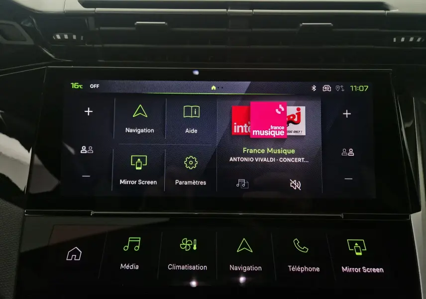 Écran tactile central du tableau de bord de la Peugeot 308 blanc Okenite, affichant navigation et musique France Musique.