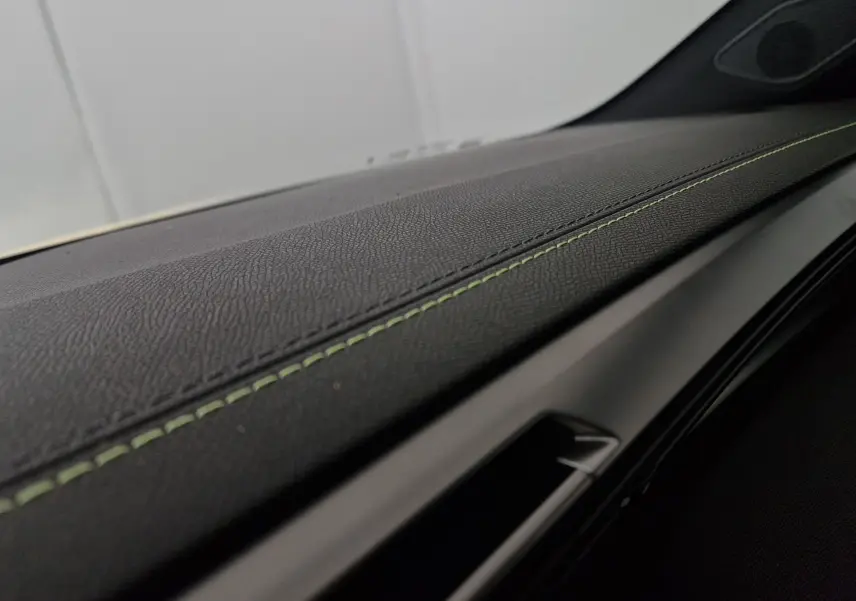 Gros plan sur la planche de bord noire avec surpiqûres vertes du Peugeot 308 GT+ Pack Vision 360 2025.