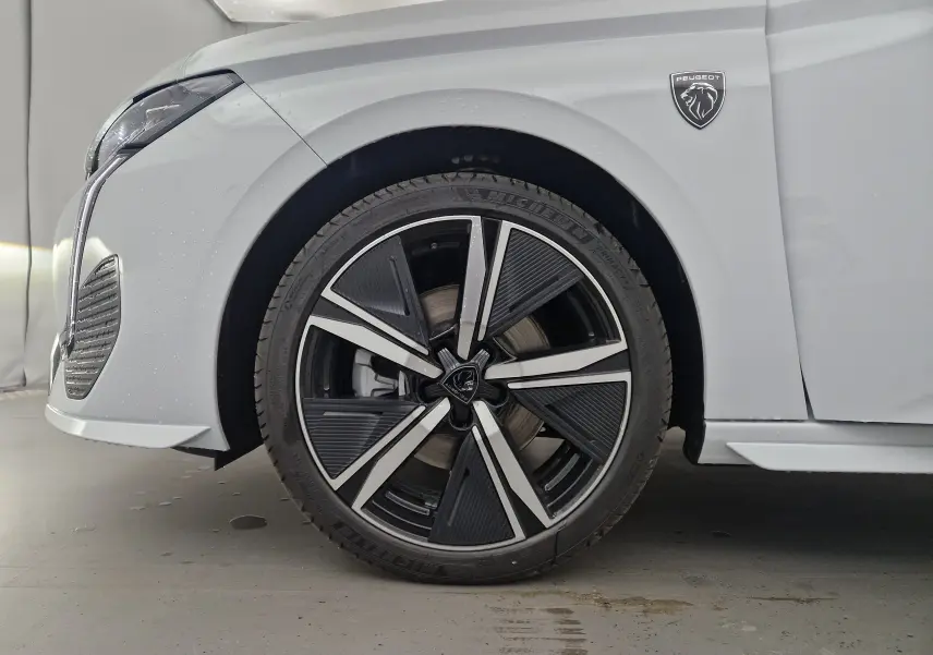 Gros plan sur la roue avant gauche et l'aile blanche Okenite d'une Peugeot 308 2025 avec logo lion noir.