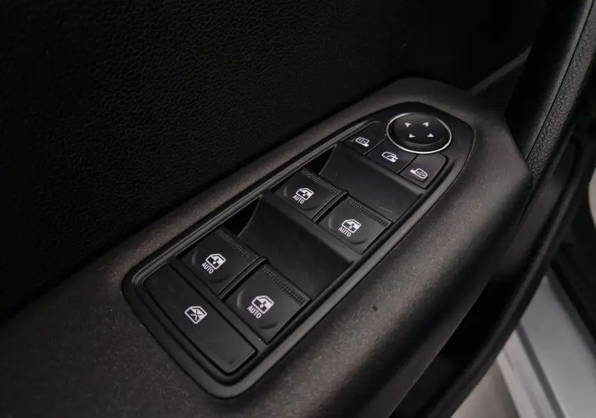 Gros plan sur les commandes des vitres électriques et rétroviseurs côté conducteur d’un Renault Captur gris Highland.