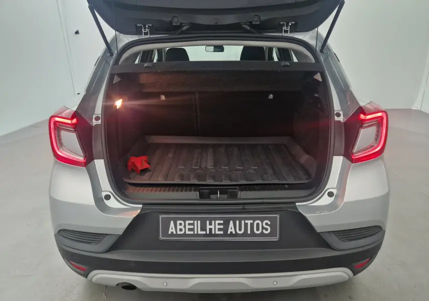 Vue arrière d'un Renault Captur gris Highland 2020 avec coffre ouvert et feux arrière allumés dans un studio.