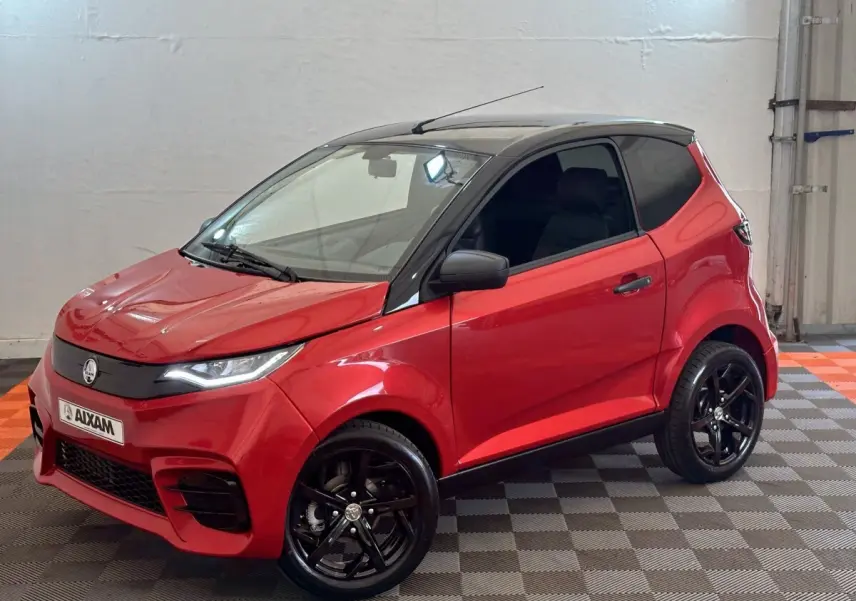 Vue 3/4 avant droite d'une Aixam Ambition 0.5 City Sport rouge avec toit noir et jantes noires brillantes.
