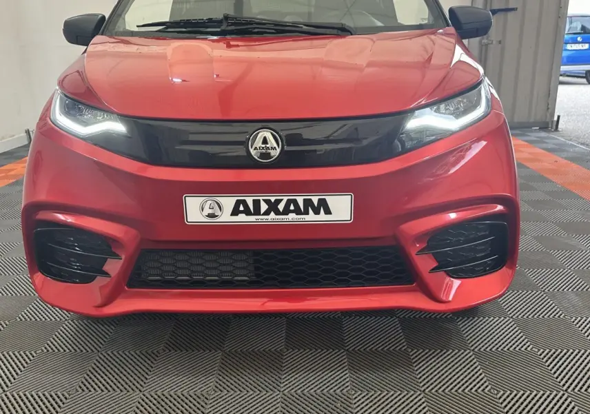 Vue frontale d'une Aixam Ambition 0.5 City Sport rouge avec phares LED et calandre noire brillante.