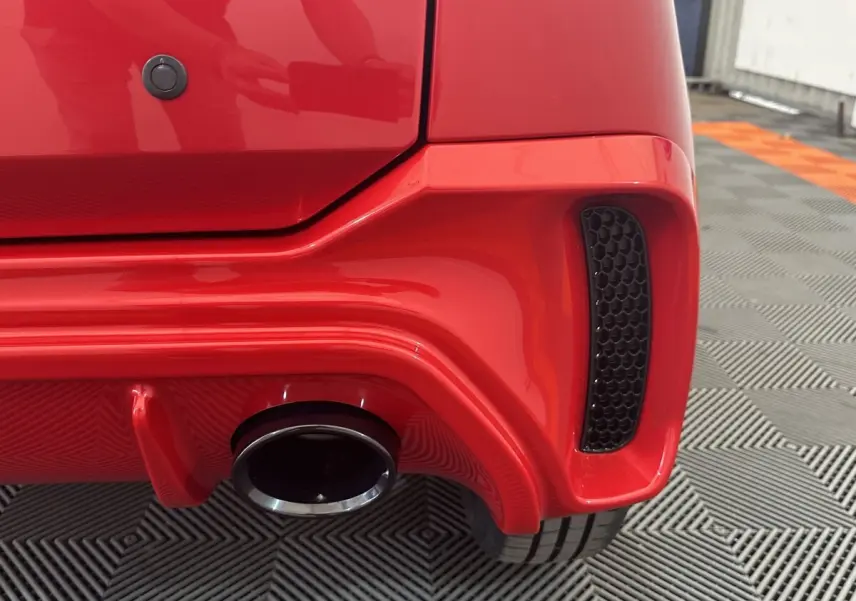 Gros plan sur l'arrière droit rouge de l'AIXAM AMBITION 0.5 CITY SPORT avec sortie d'échappement et diffuseur.