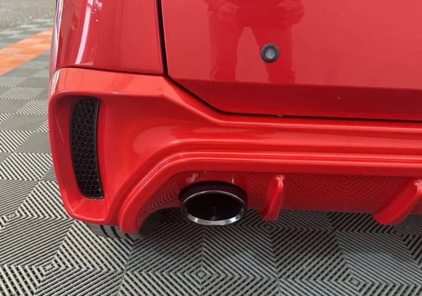 Gros plan sur l’échappement arrière droit d’une Aixam Ambition 0.5 City Sport rouge, soulignant le diffuseur et la sortie chromée.