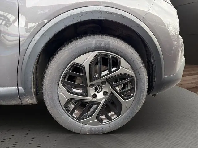 Gros plan sur la roue avant droite d'une Citroën C4 gris platinium, mettant en valeur la jante alliage au design moderne.