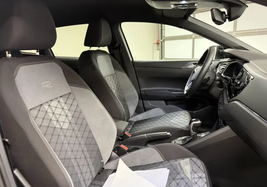 Vue intérieure côté conducteur du Volkswagen Taigo 1.5 TSI R-Line 2025, sièges tissu et alcantara gris avec surpiqûres.