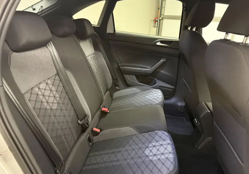 Vue intérieure arrière côté gauche du Volkswagen Taigo 1.5 TSI R-Line 2025, sièges tissu noir et gris à motif géométrique.