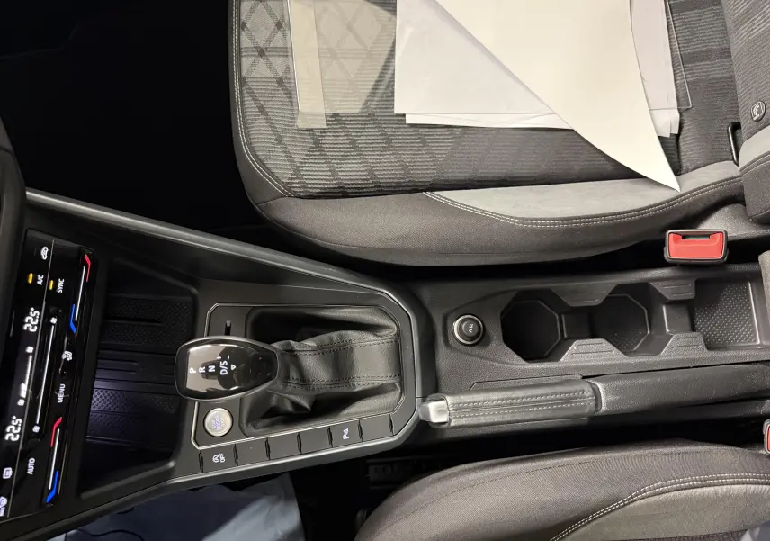 Vue intérieure centrée sur la console centrale du Volkswagen Taigo 1.5 TSI 150 DSG7 R-Line Edition avec levier de vitesse et sièges gris.